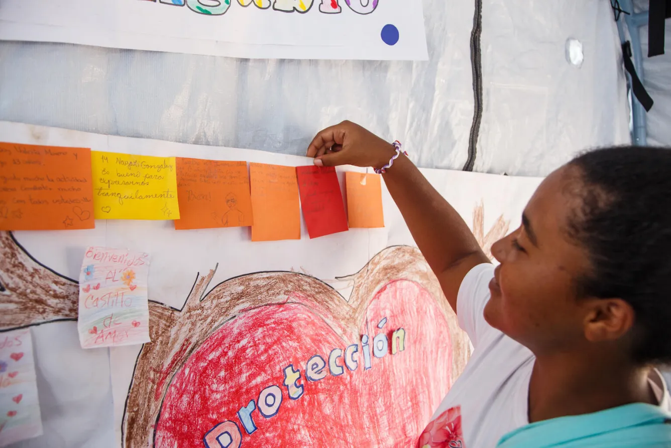 A child places a sticky note on the wall.