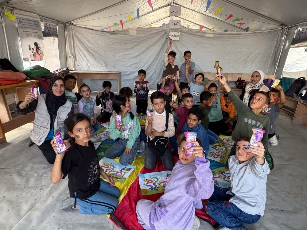 In a tent, a group of children each hold up a bar of soap to the camera.