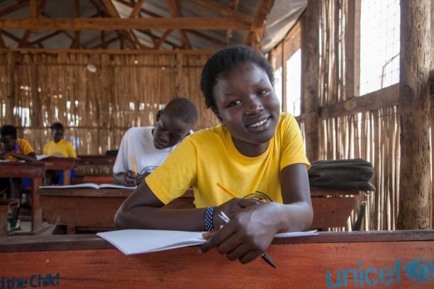 15-year-old Martha smiles at the camera while sitting in a classroom in South Sudan.