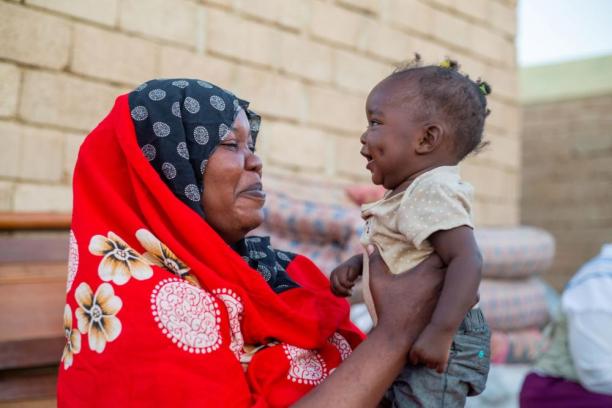 In Sudan, a smiling mother holds up her 10-month-old daughter.