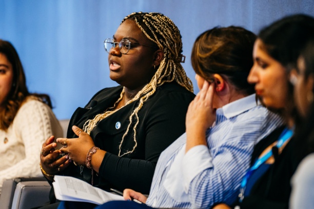 A youth is seated and speaking in a group setting.