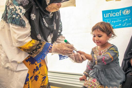 In a UNICEF-supported health clinic in Afghanistan, a girl has her finger marked following an oral polio vaccination by a health worker.