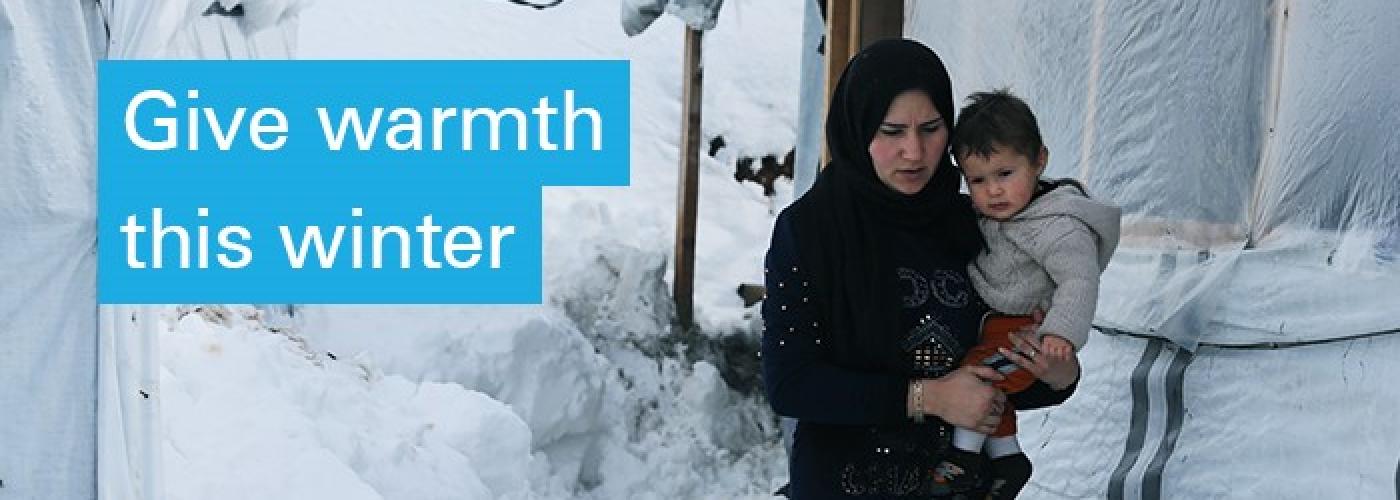 A mother and toddler try to stay warm after a big snowfall. Text on image: Give Warmth this Winter