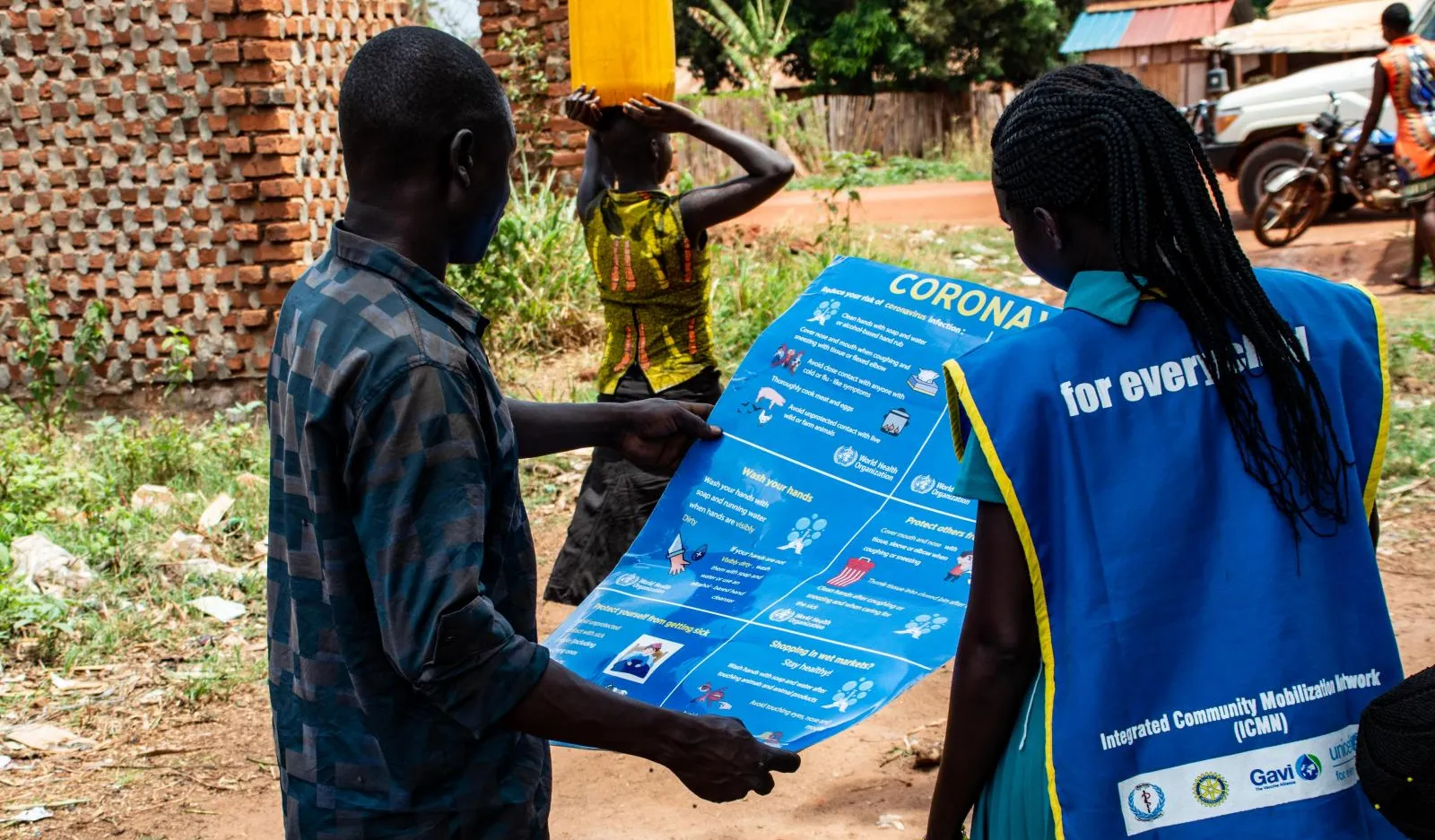 Community staffers inspect a COVID-19 education poster.