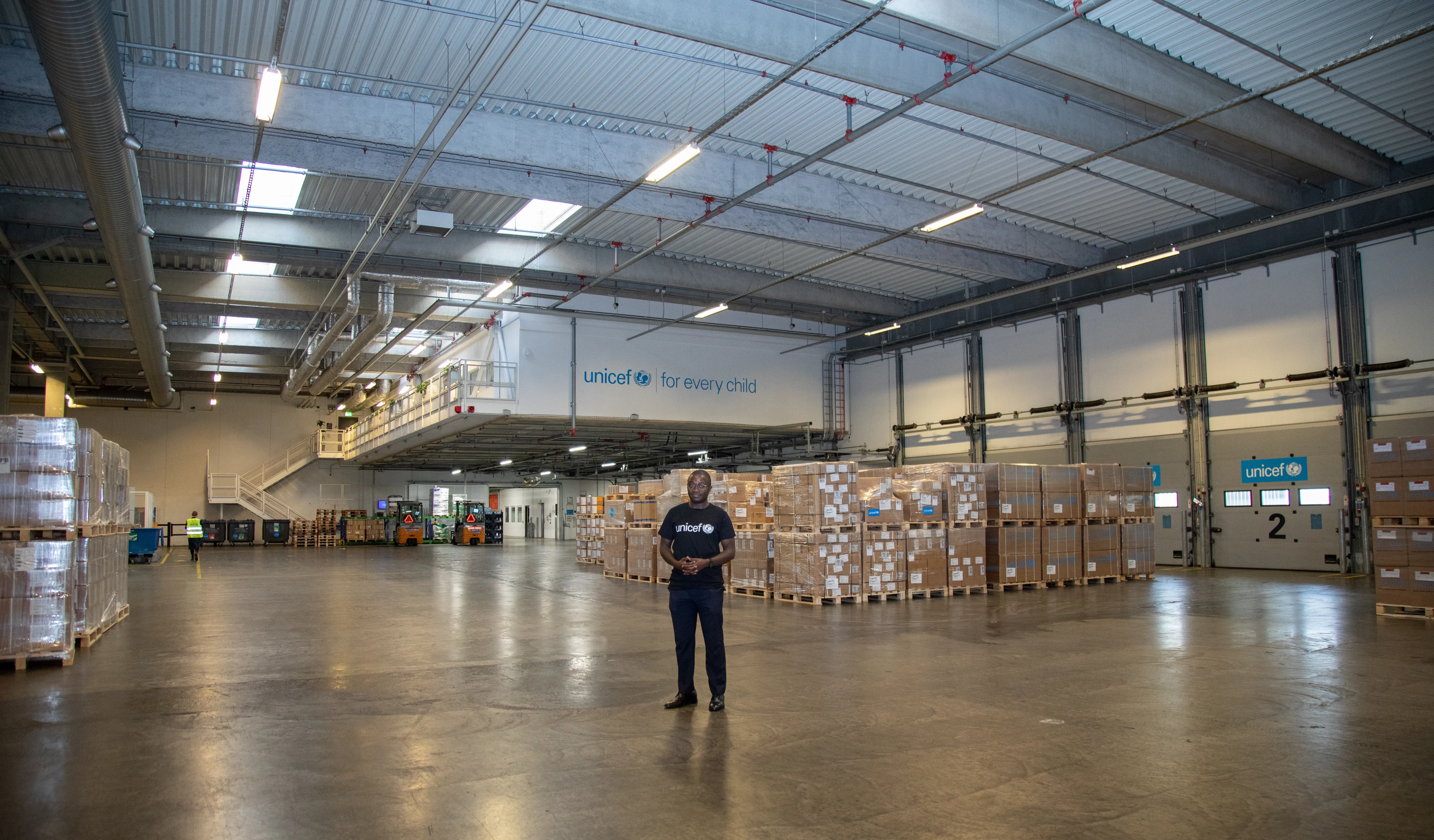 A man stands in a warehouse with lots of boxes behind him.