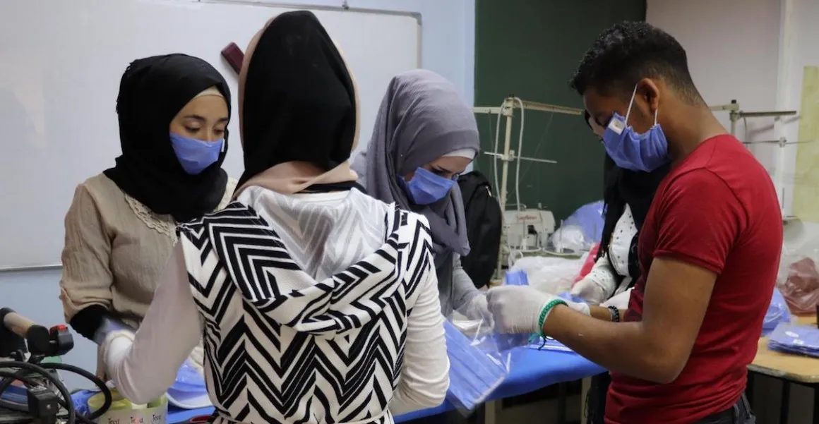 Syrian youths work to make cloth masks.