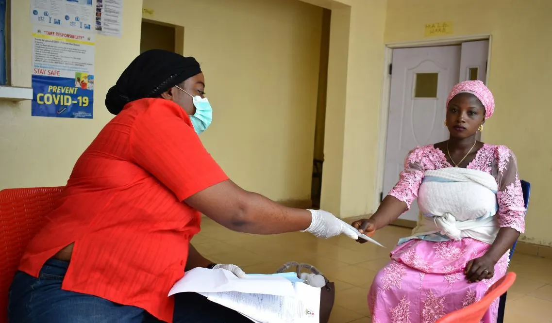 A registrar shows a new mother a birth registration form.