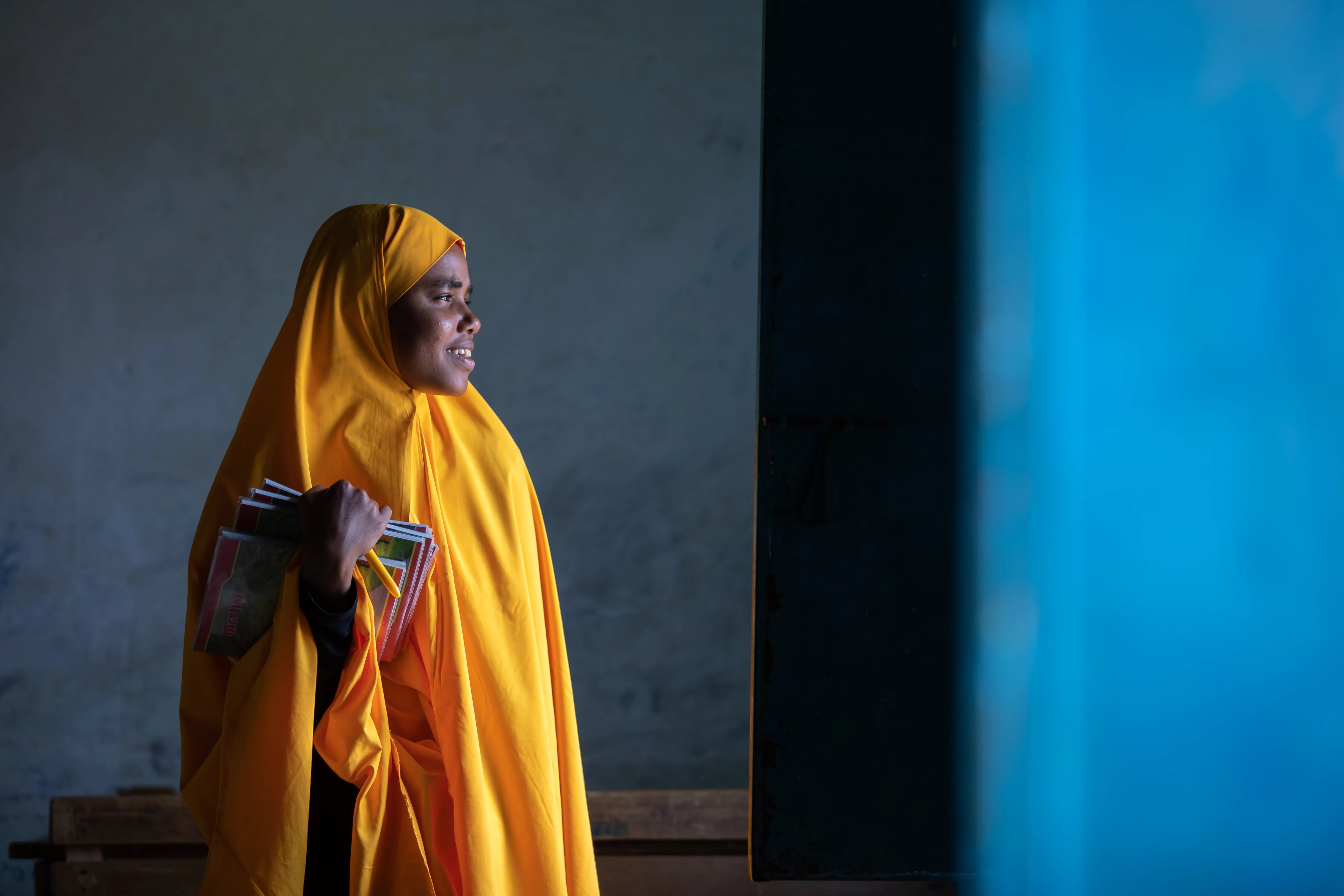 Une fille portant un uniforme jaune en Somalie regarde avec espoir vers la lumière.