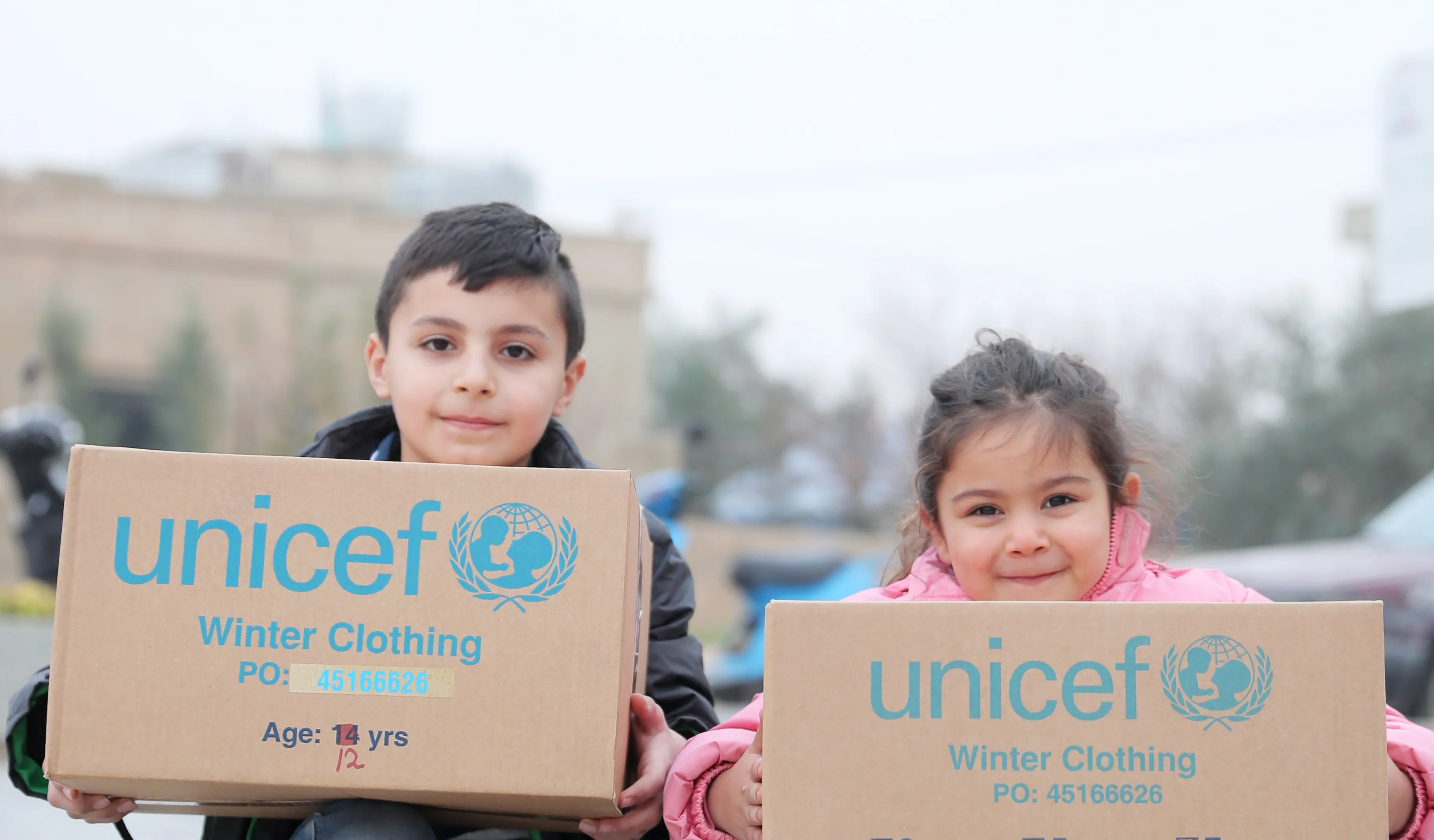 Two children show off their UNICEF supplies in Lebanon.