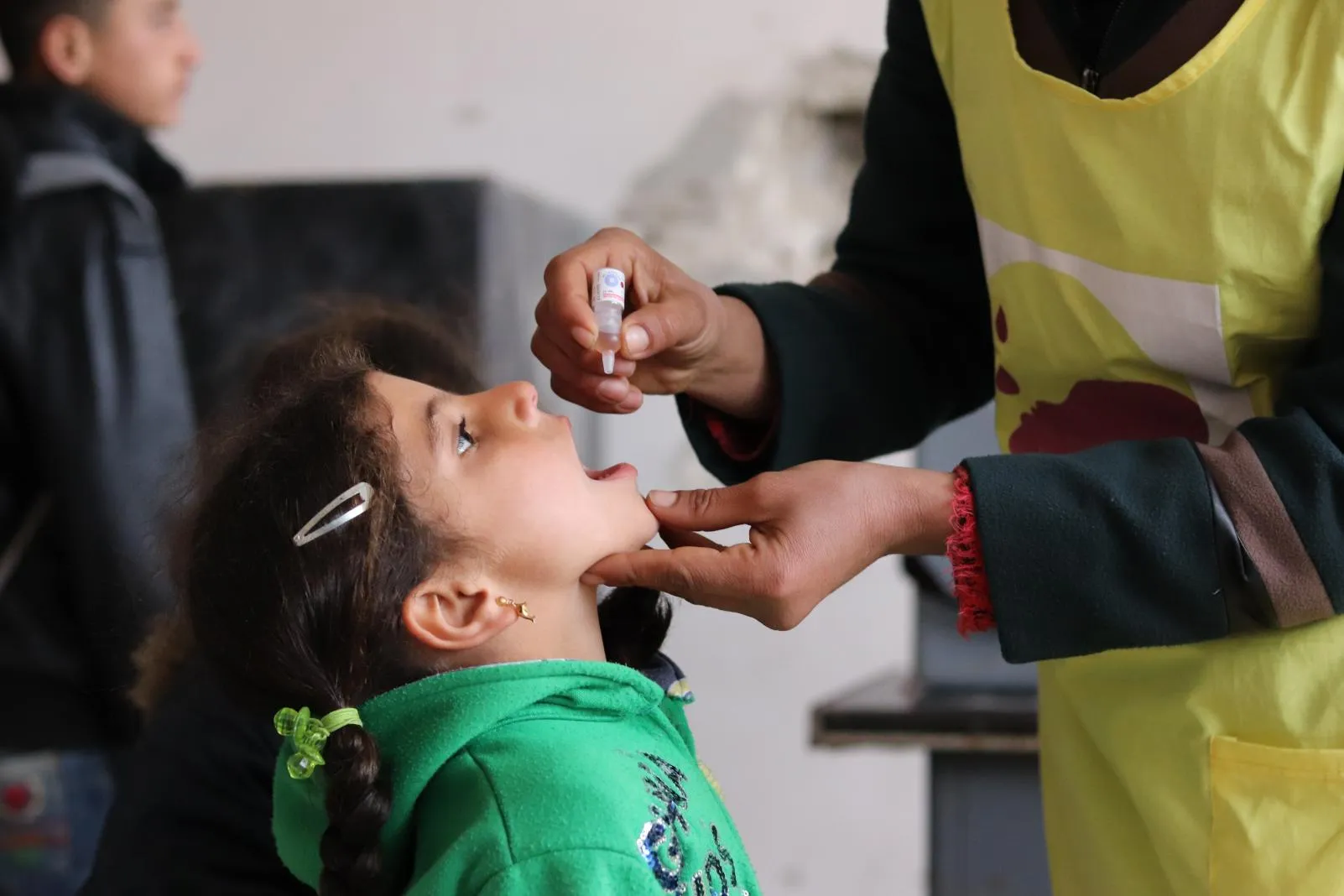 A girl receives an oral polio vaccine dose by a UNICEF worker during an immunization campaign in Aleppo, Syria. 