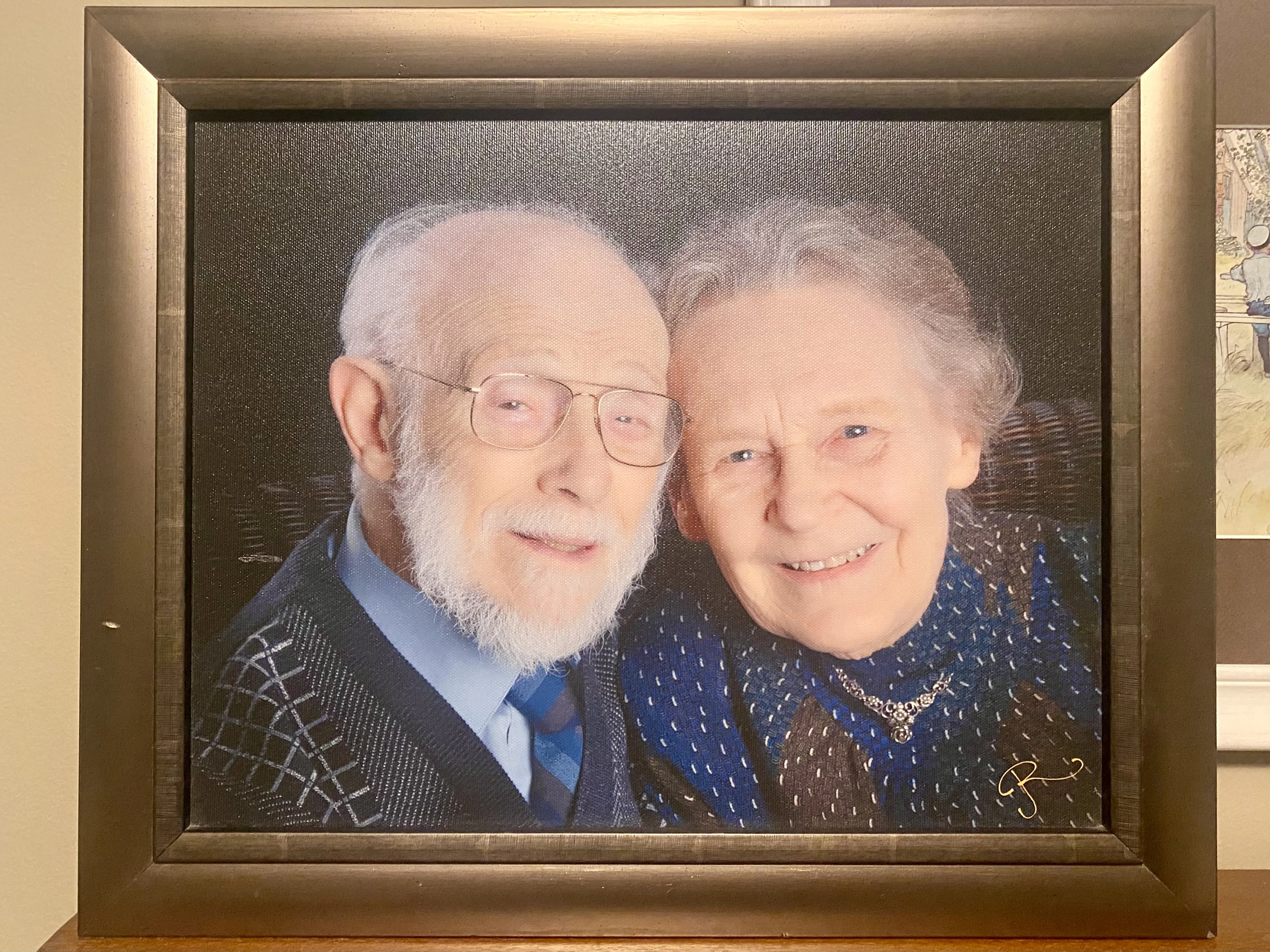 A photo of a framed photo of an elderly couple looking at the camera smiling with their heads touching. 