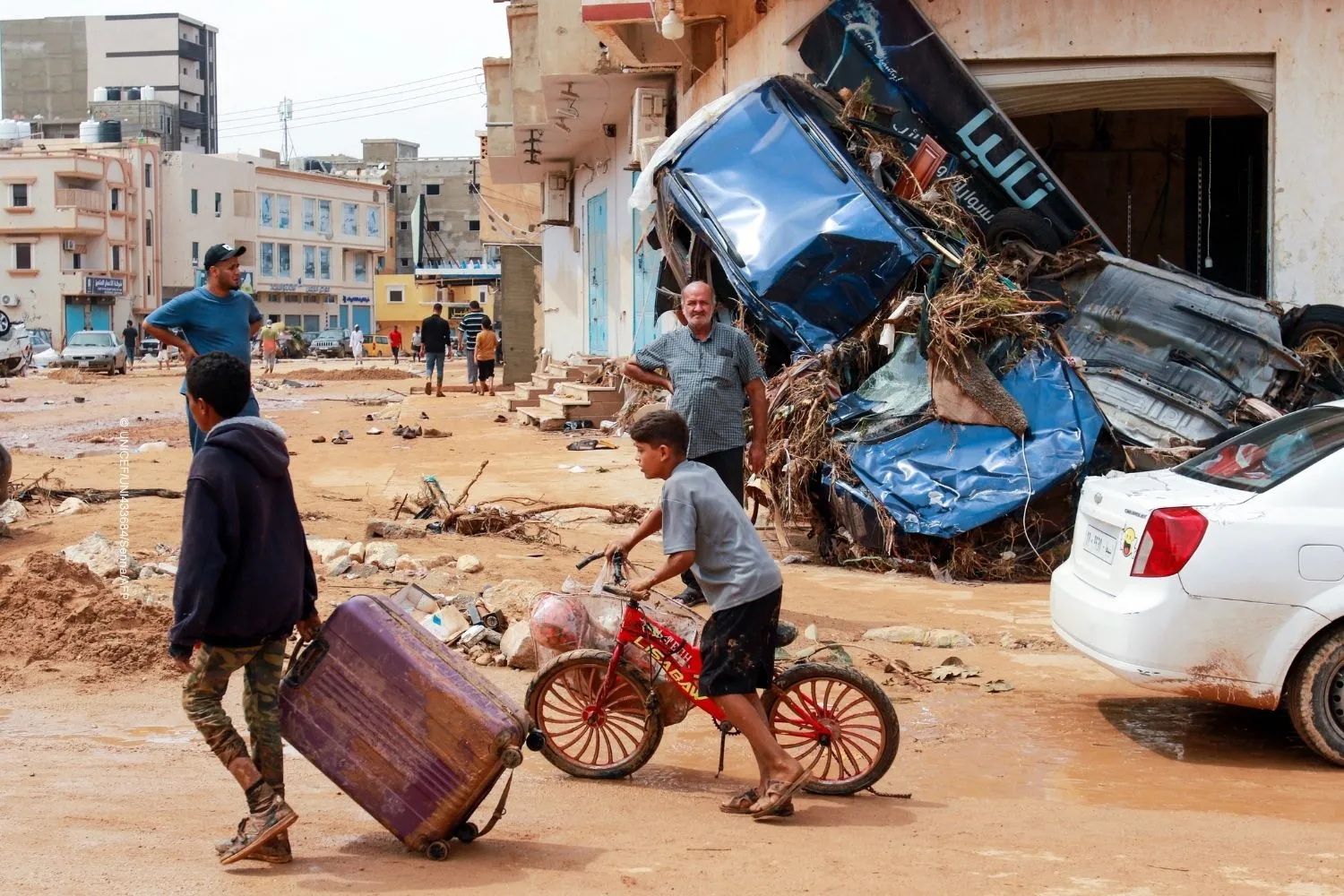 A boy pulls a suitcase past debris in a flash-flood damaged area in Derna, Libya.
