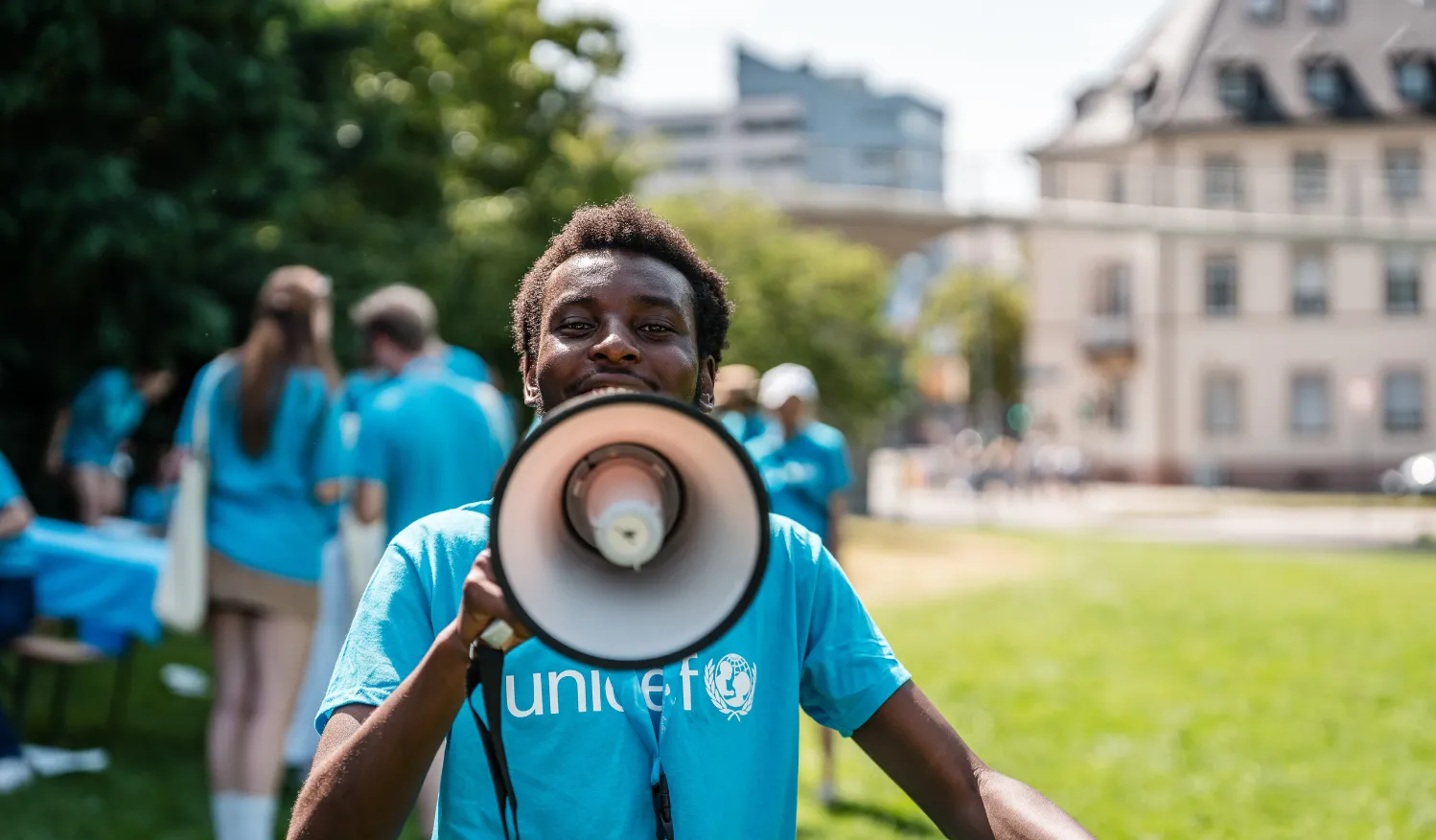 Youth in a blue UNICEF t-shirt speaking into a megaphone.