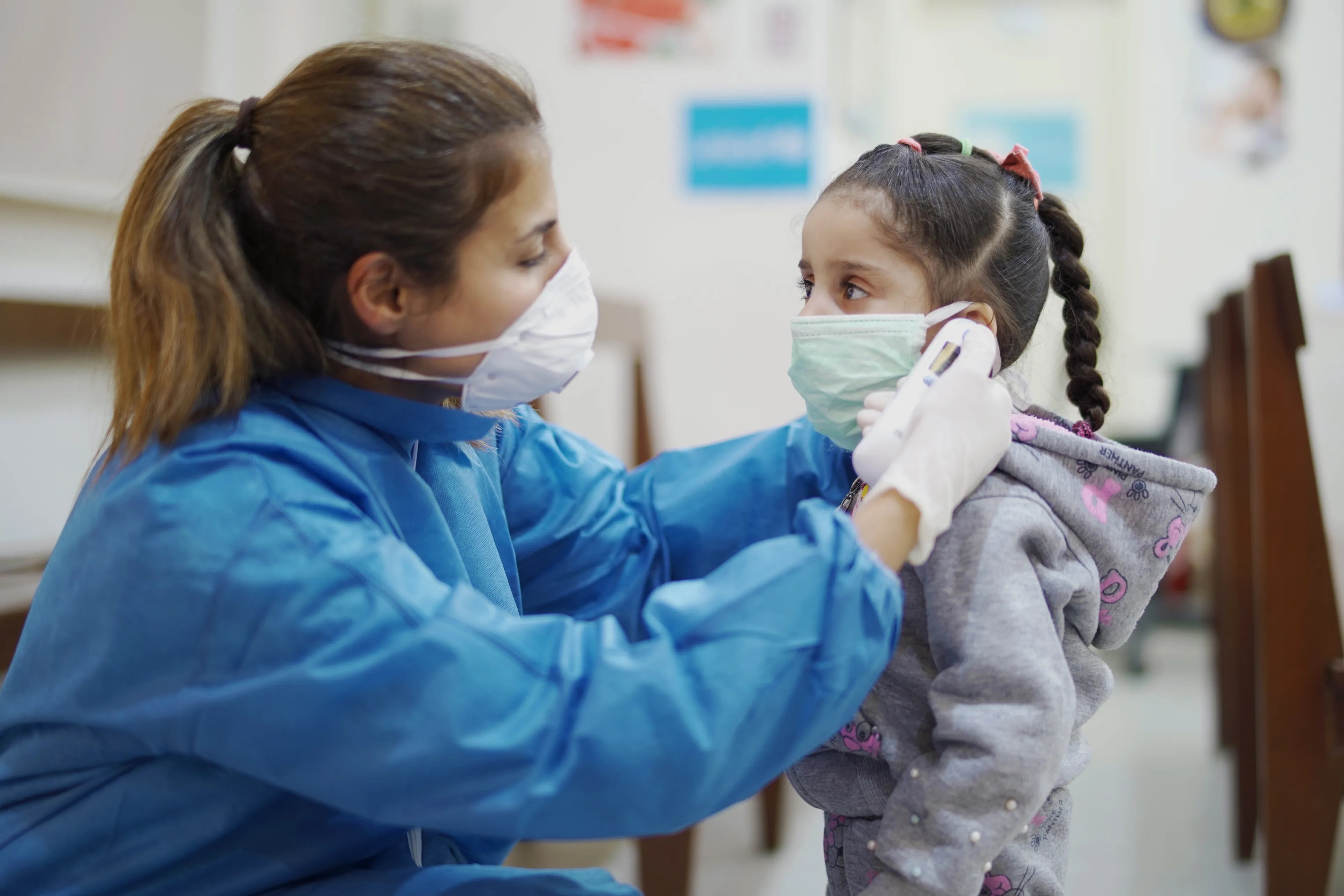 Nurse in Lebanon helping little girl put on face mask