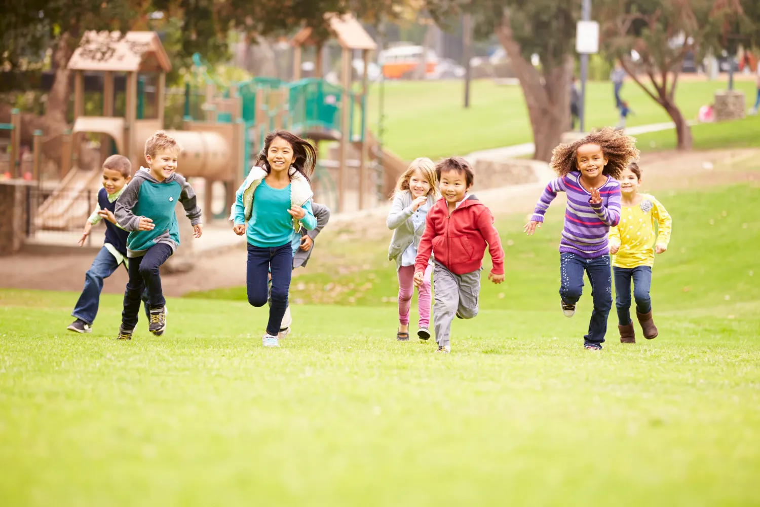 Seven children running towards the camera in a playground