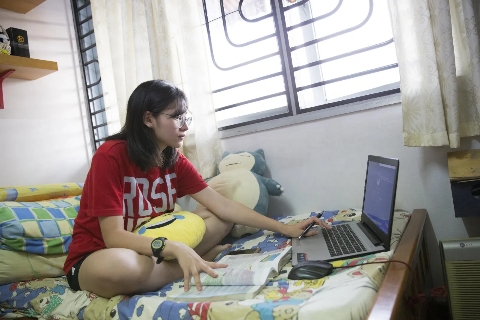 Youth sits on her bed reading laptop screen