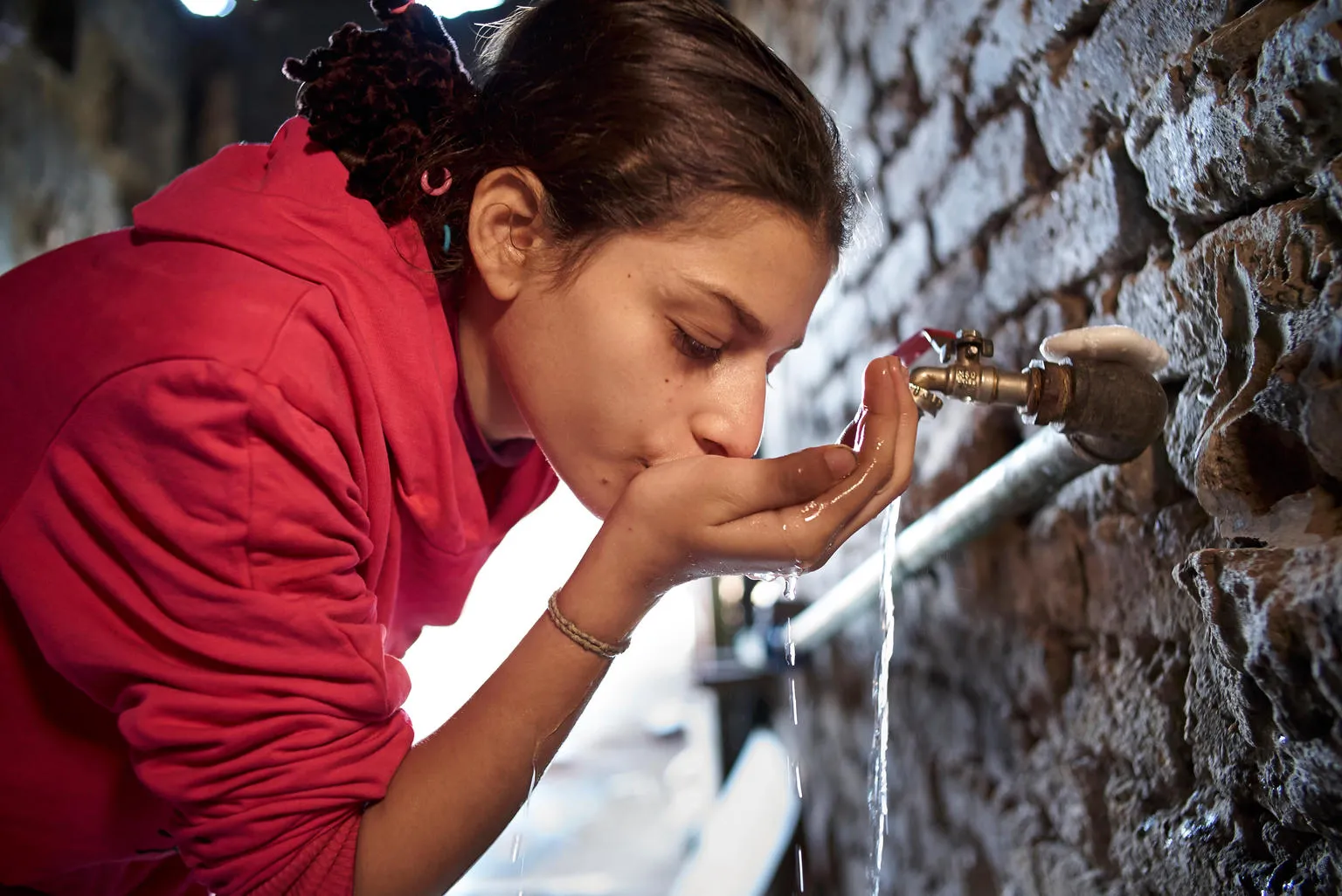 A girl drinks clean water from a tap.