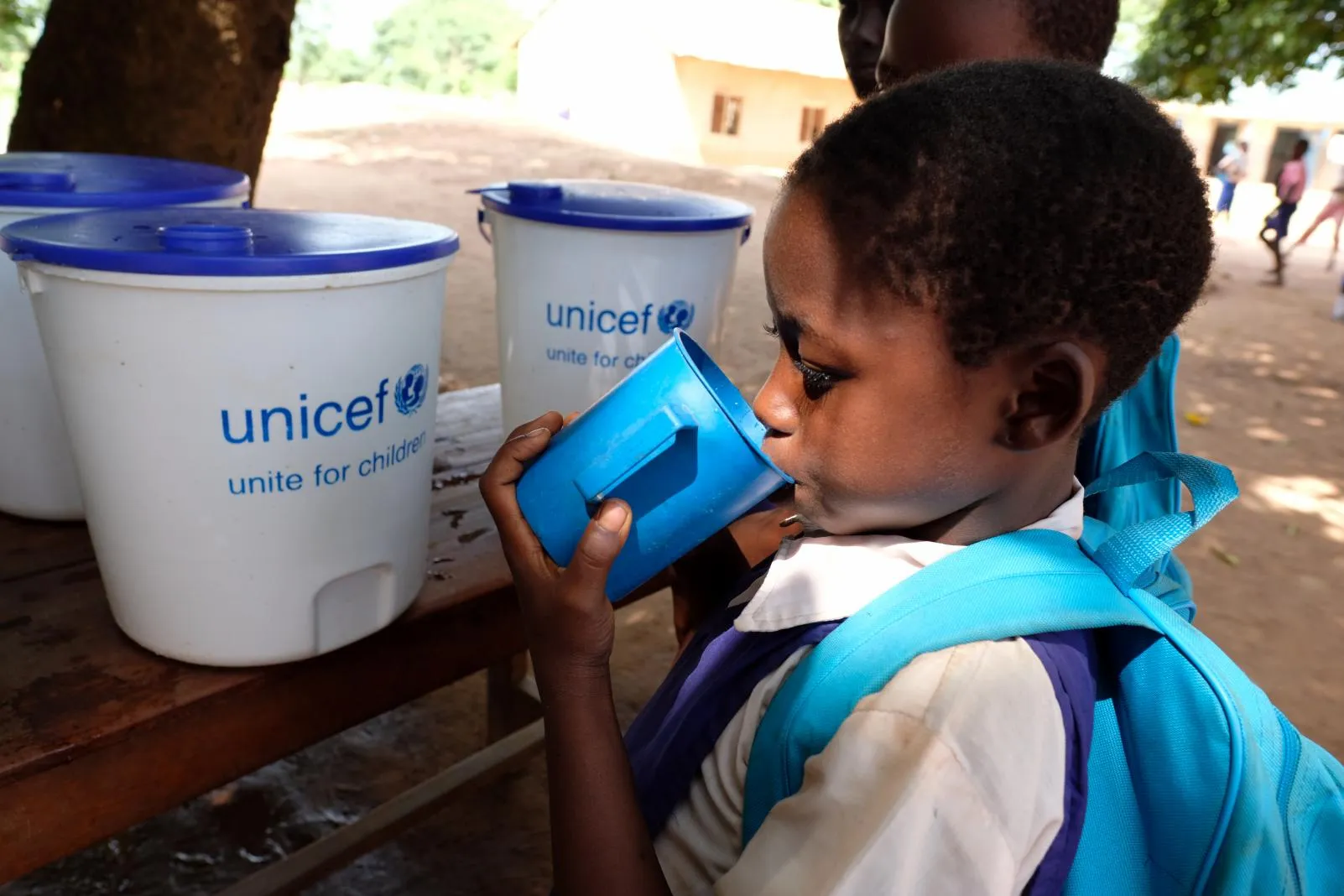 A student drinks from a cup with a UNICEF logo.