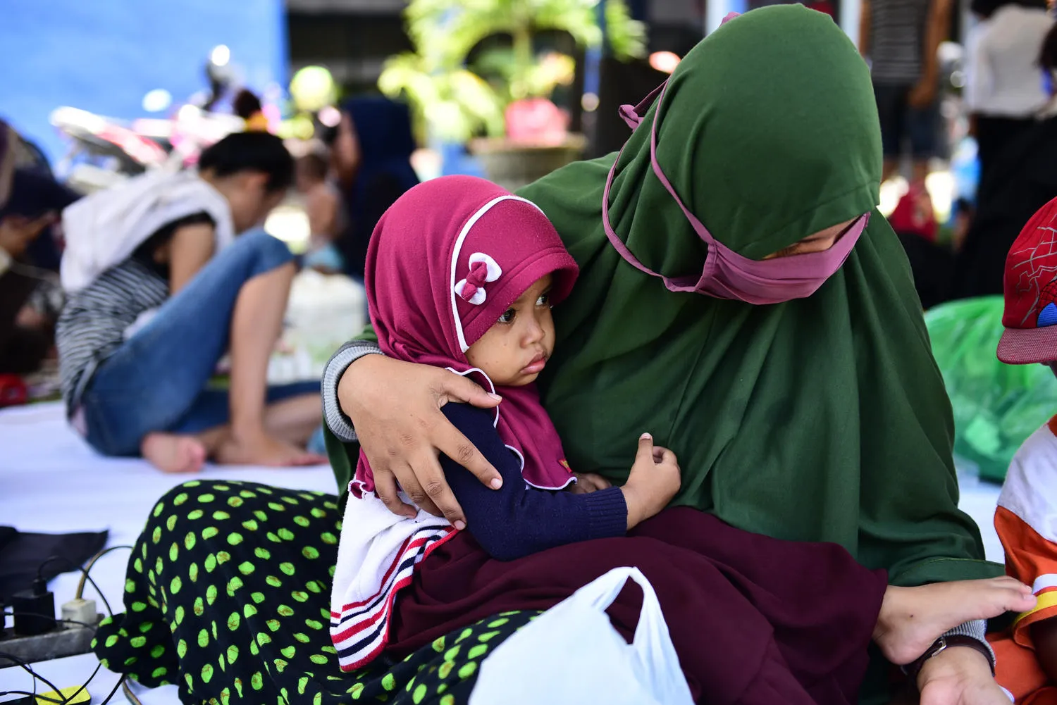 A baby sits in her mother's lap at a temporary shelter in Palu in 2018.