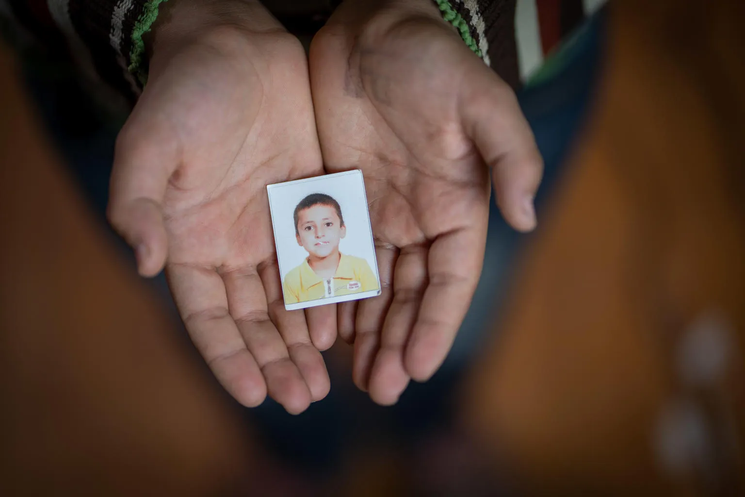 A Syrian boy holds a photo of himself in kindergarten.