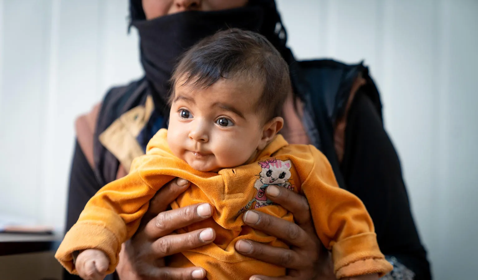 A baby waits to receive new winter clothes in Zaatari Refugee Camp, Jordan.