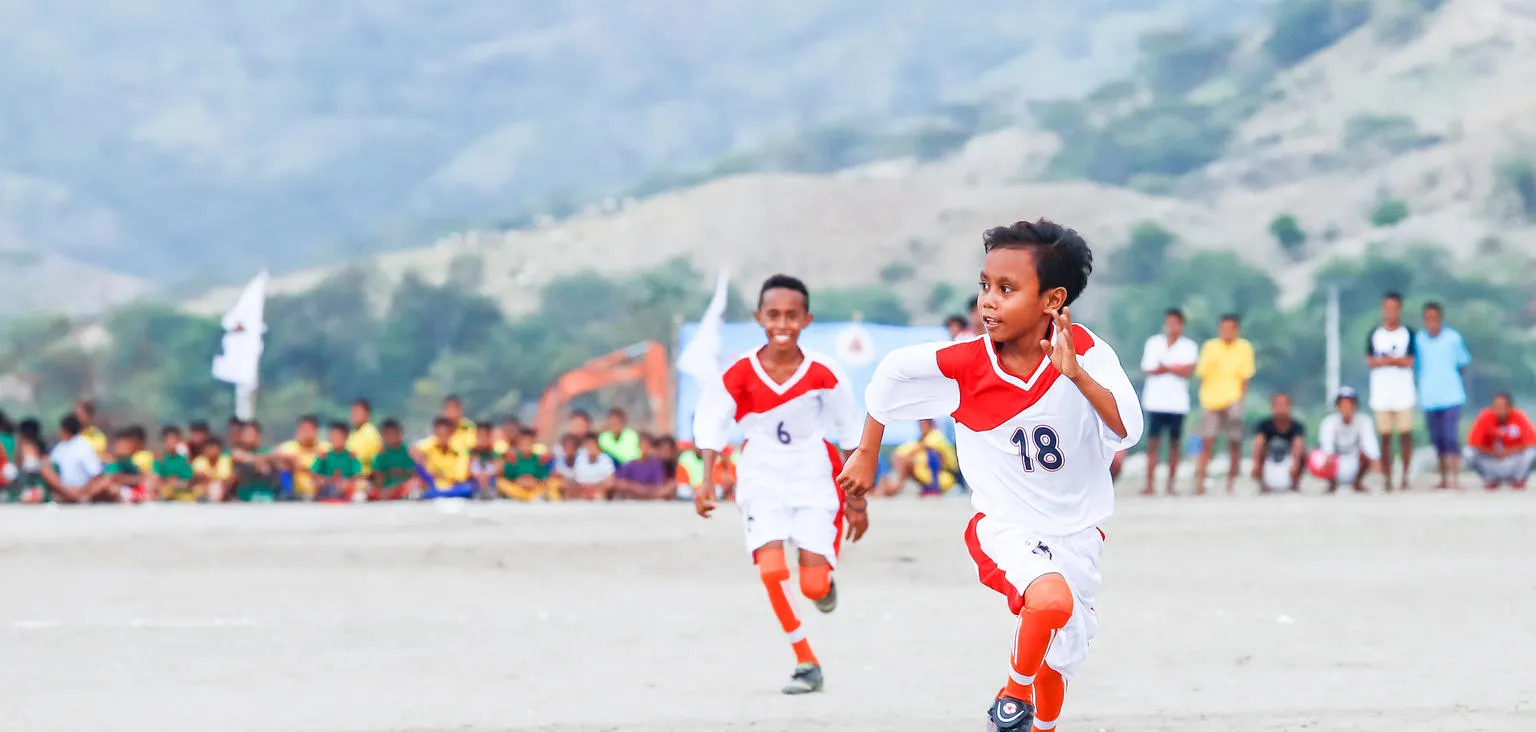 Two boys take part in a soccer match.