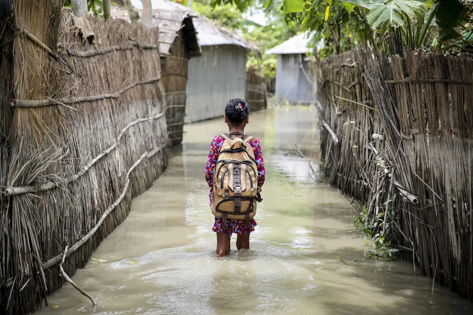  Child wades through water on her way to school in Bangladesh