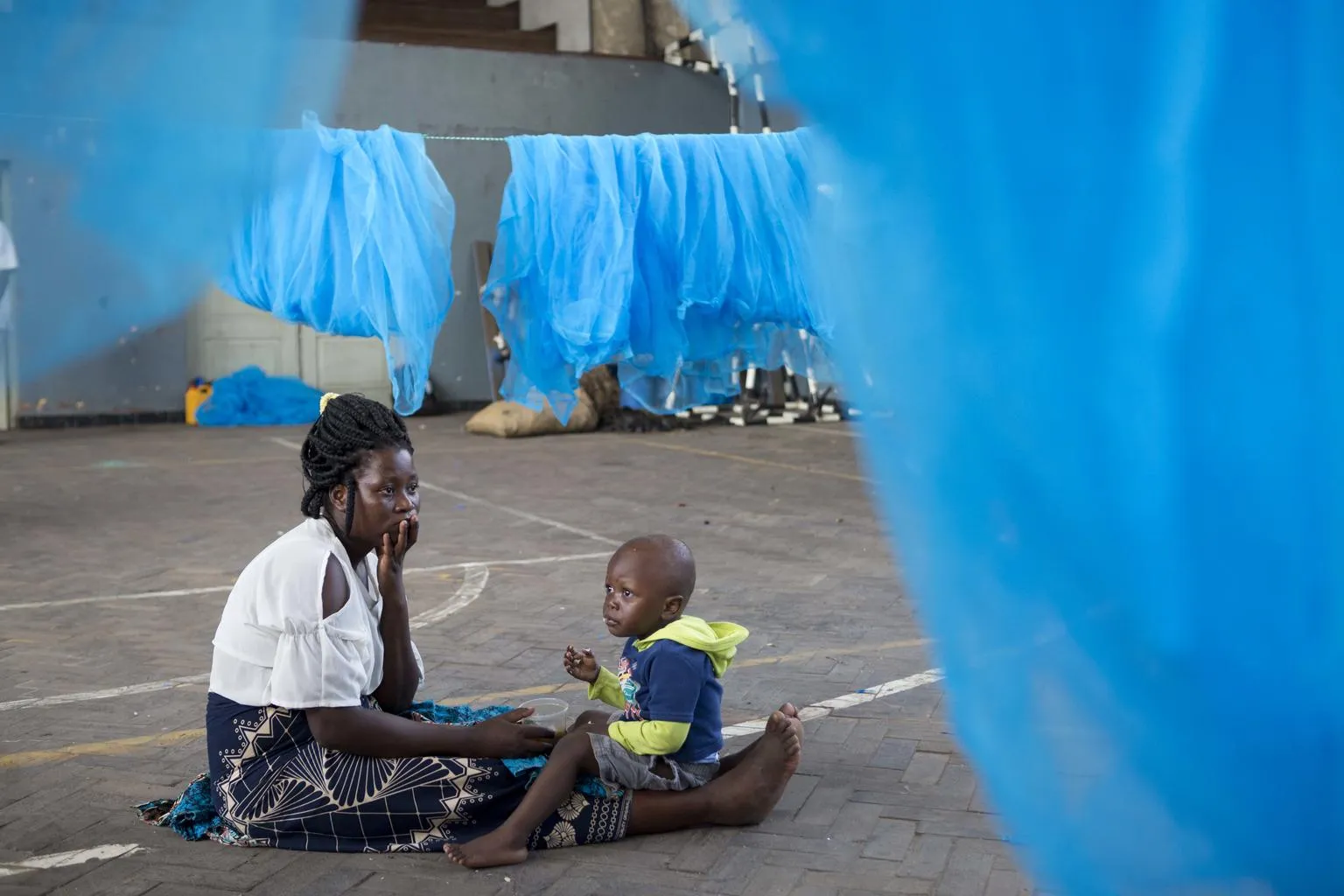 woman and chjld surrounded by mosquito nets