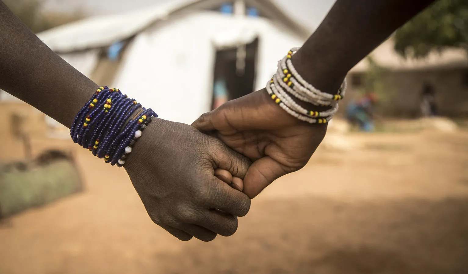 Two girls hold hands outside a UNICEF supported centre.