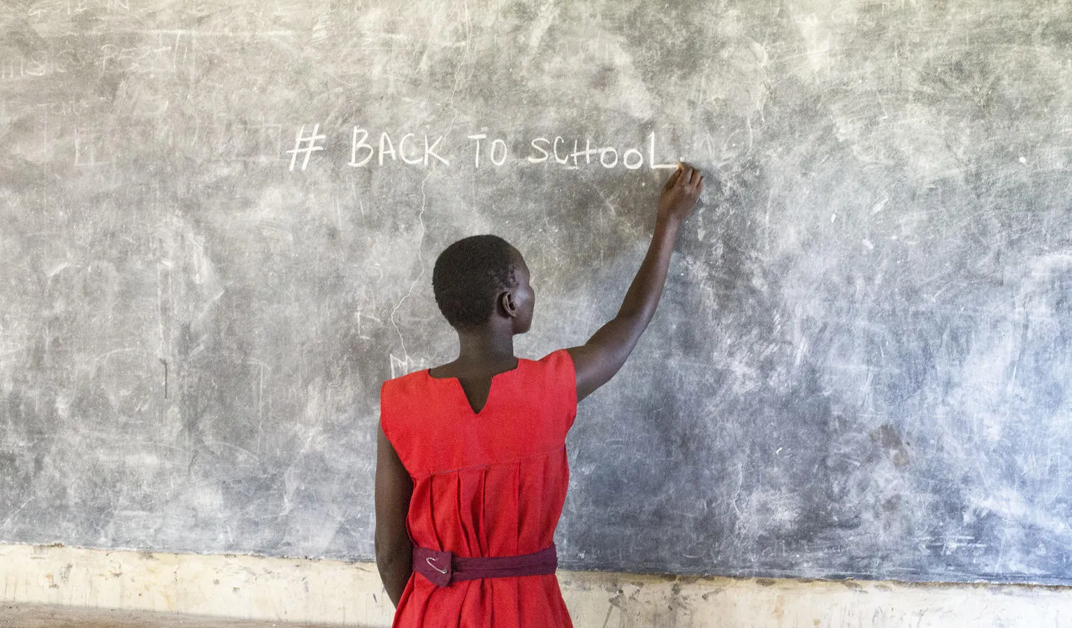 A girl writes on a chalkboard in a classroom in Uganda.