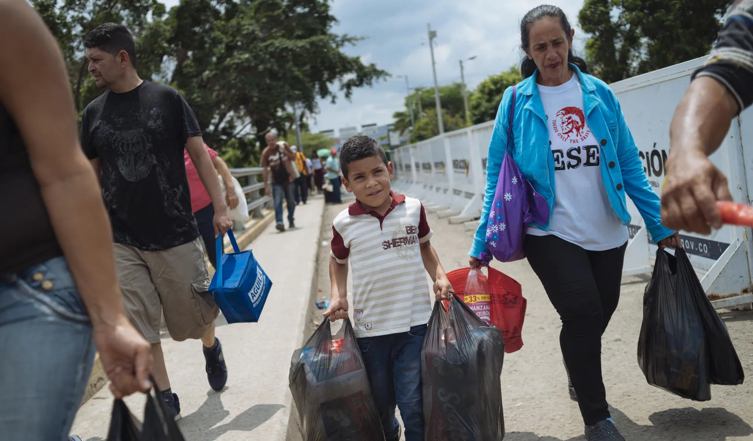Luisyan Diaz, 7 years old, helps his grandmother and mother cross the border on the Simon Bolivar Bridge in Colombia, from their home in Venezuela.