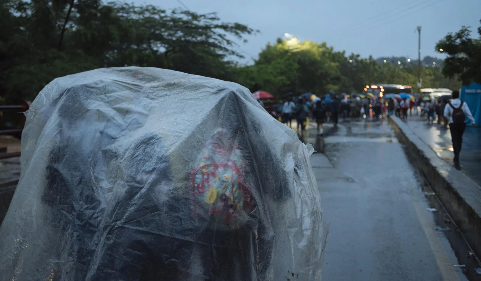 Children shelter under a plastic tarp while waiting to cross the border from Venezuela.