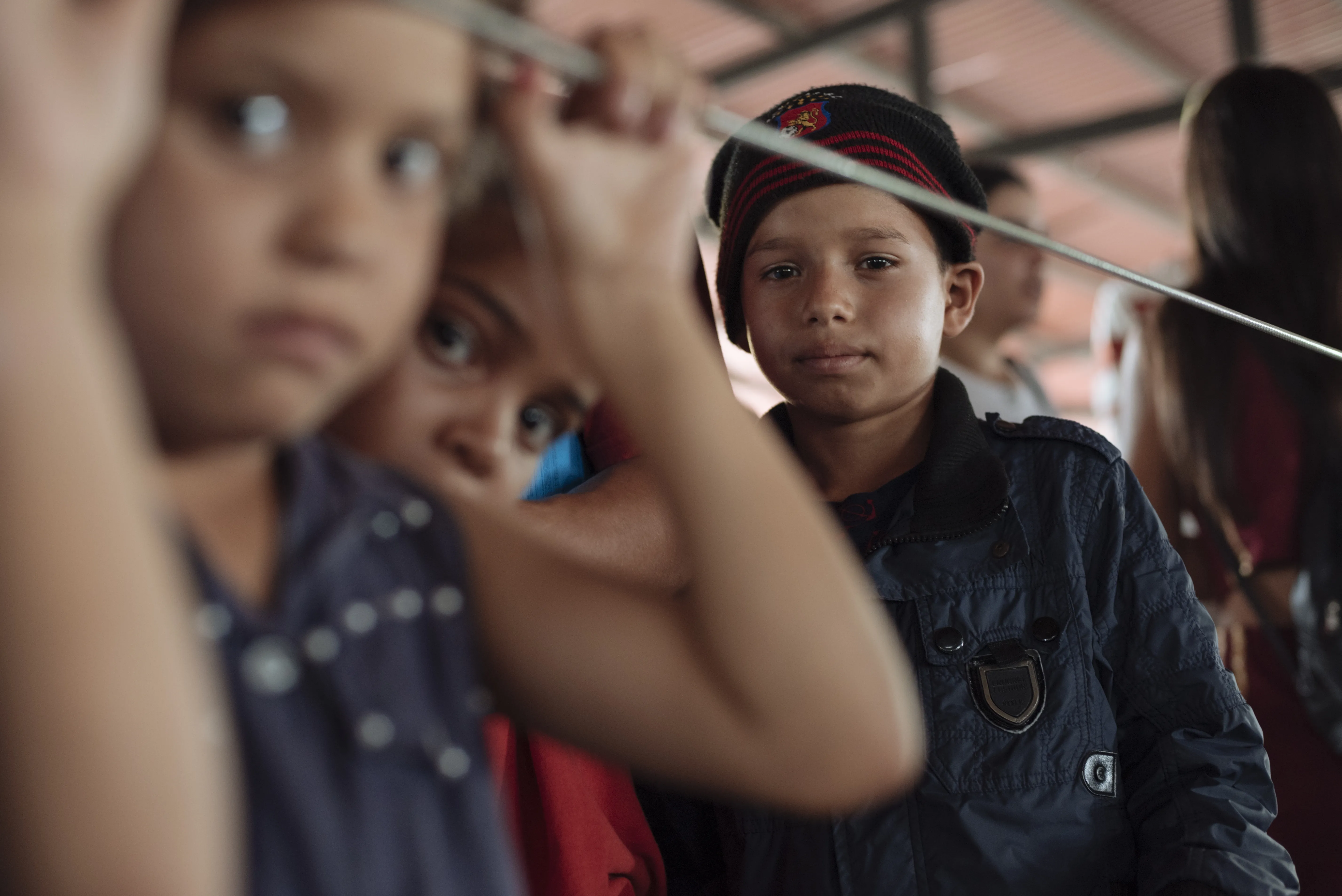 Three boys in a migrant camp tent