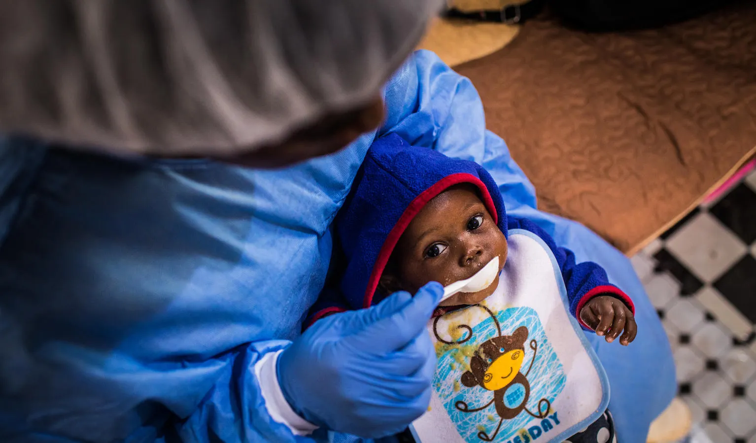 Christ-Vie, an Ebola orphan, is fed by a caretaker in Butembo.