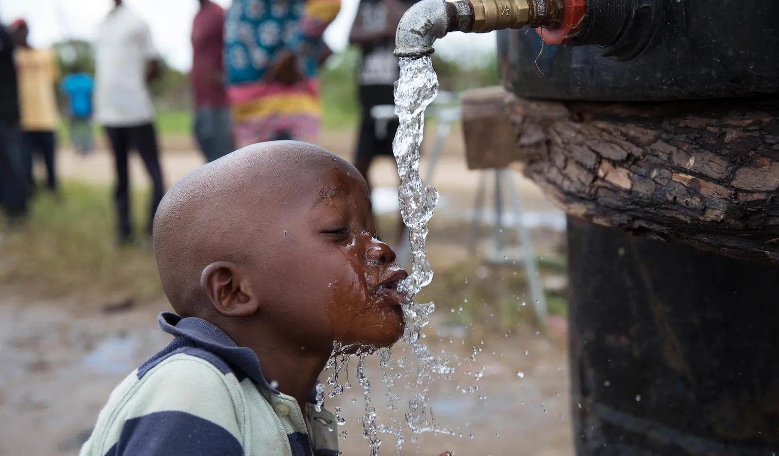 A child drinks from a water point at the Samora Machel II accommodation centre.