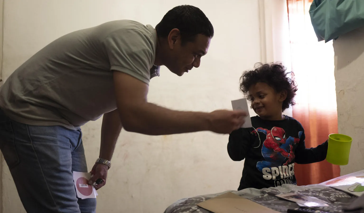 A father helps his son brush his teeth.