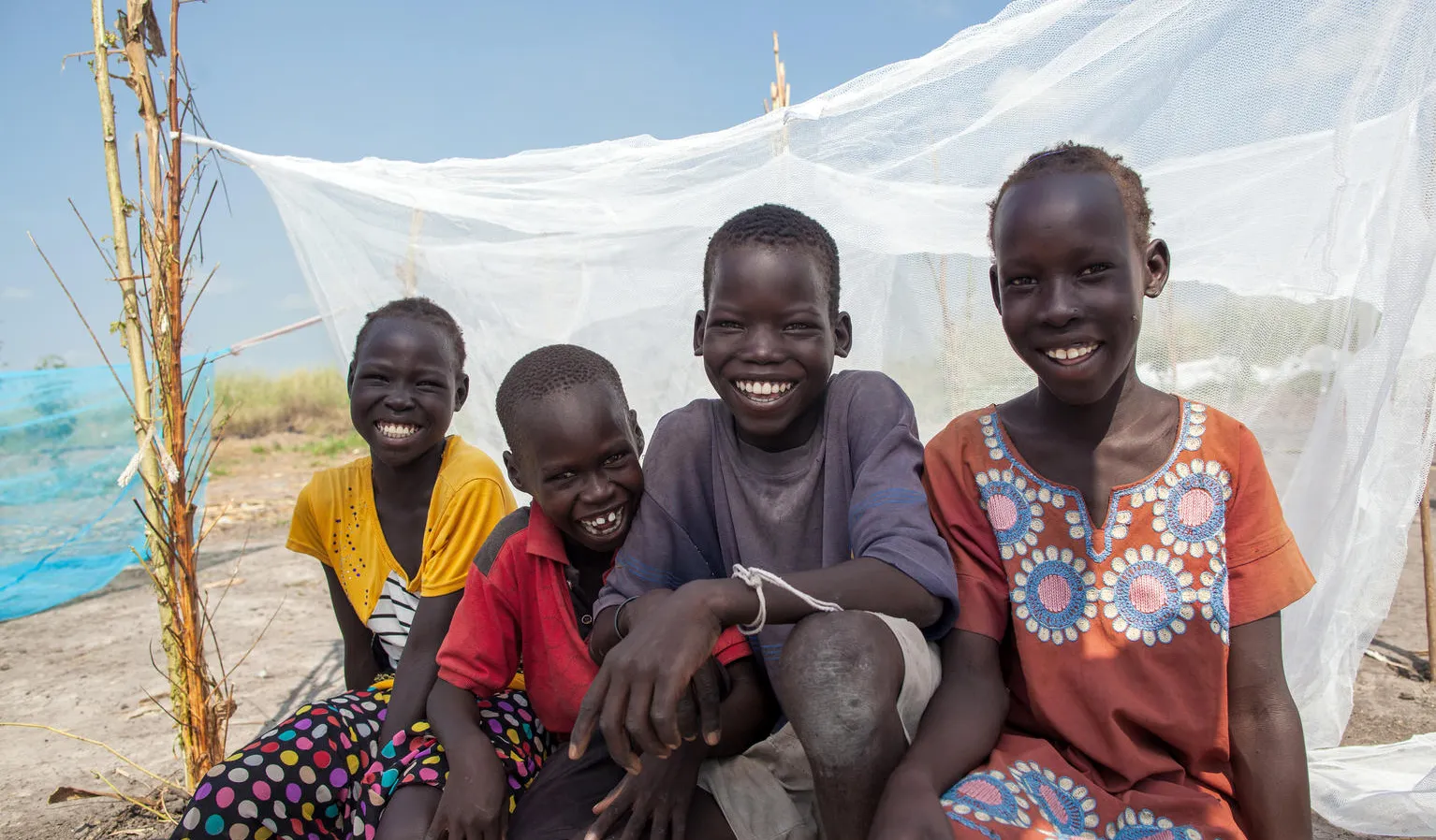 Friends sit by a UNICEF-supplied mosquito net in Bienythiang in Akoka county, Upper Nile state, South Sudan.