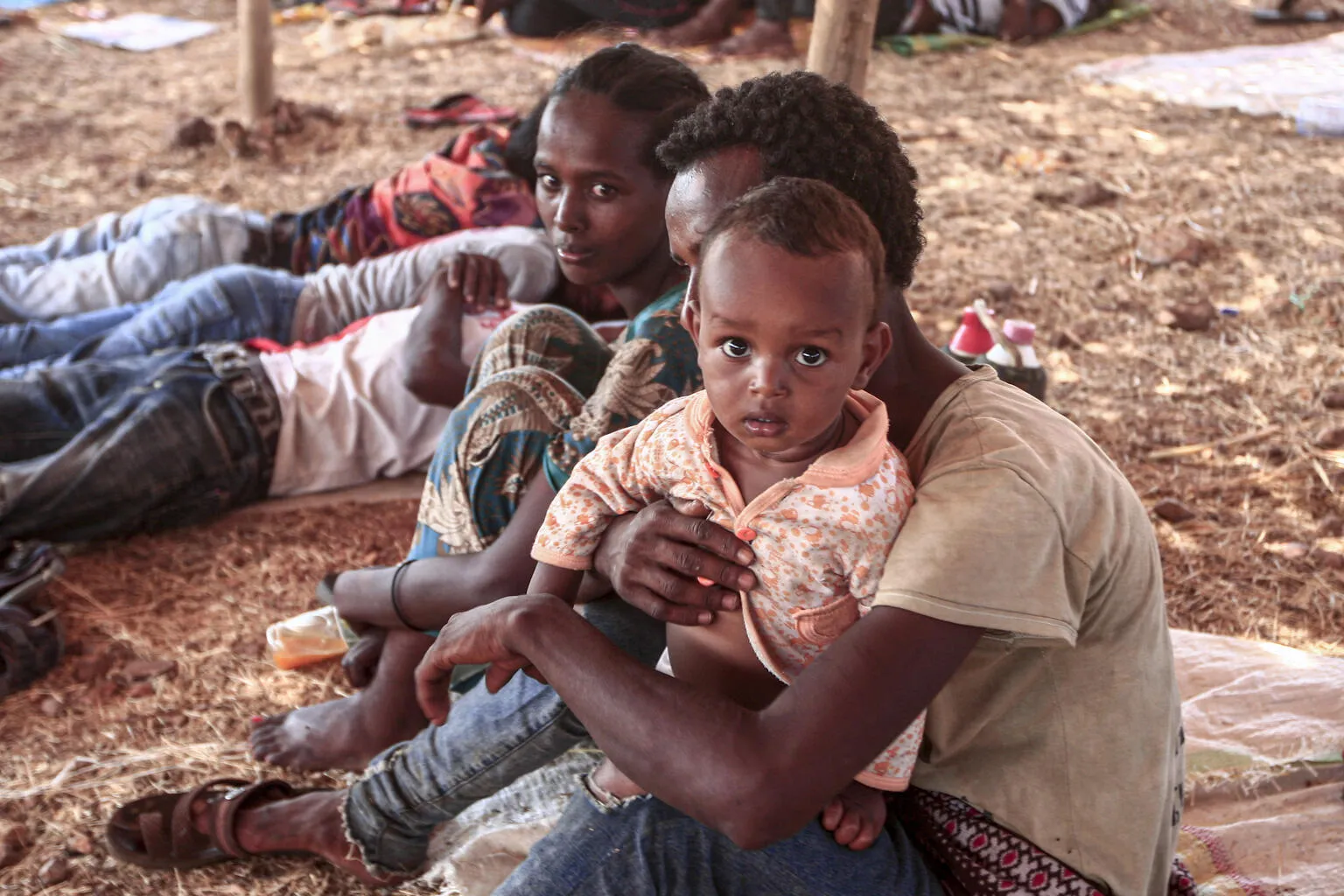 An Ethiopian refugee child who fled fighting in Tigray province sits holding a child in a hut at the Um Raquba camp in Sudan's eastern Gedaref province, on 16 November 2020. Sudan – one of the world's poorest countries, now faced with the massive influx – has reopened the camp, 80 kilometres (50 miles) from the border. It once housed refugees who fled Ethiopia's 1983-85 famine that killed over a million people.