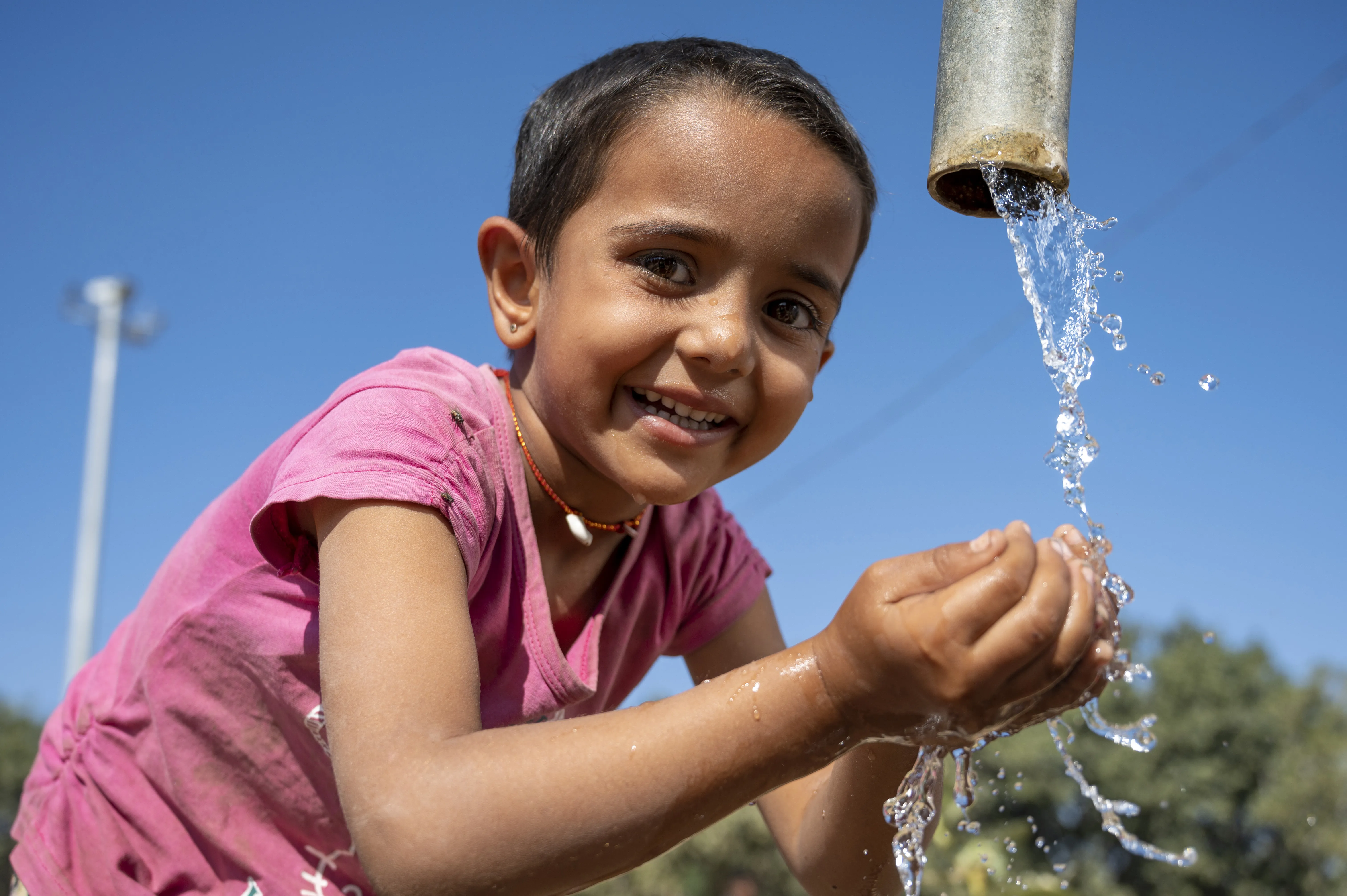 Jhanu (5 yrs) drinks water from the village hand pump near her anganwadi. 
