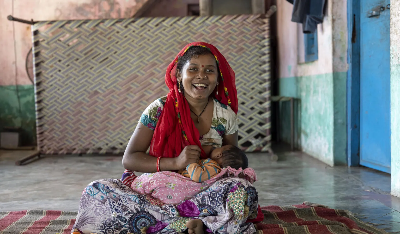 A young mother breastfeeds her newborn baby at a tea estate in India.