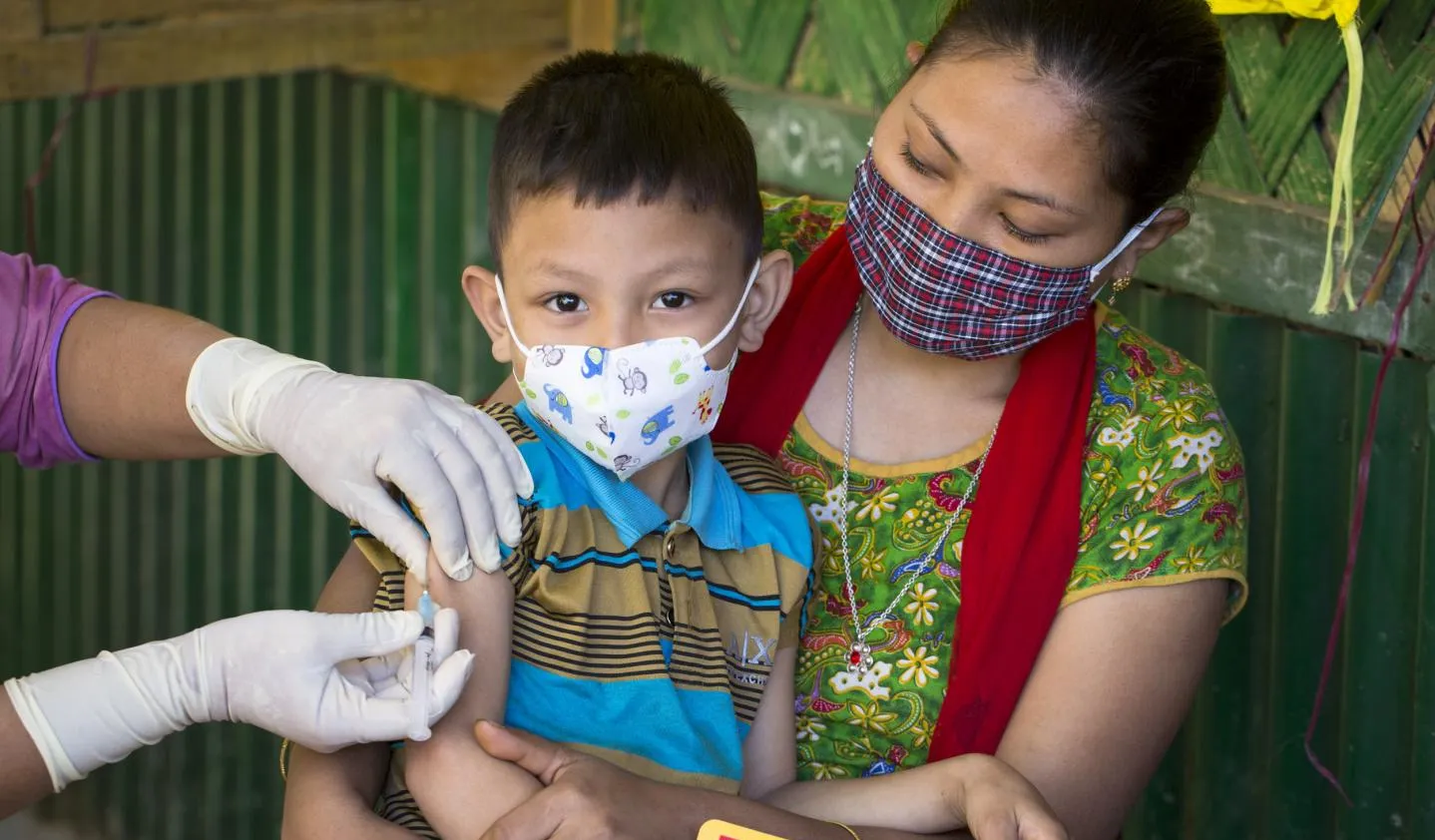 A child sits on his mother's lap as he receives an MMR vaccine.
