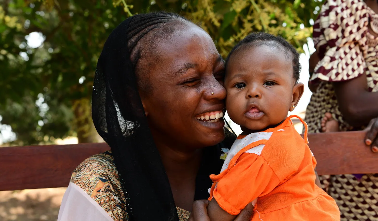 A mother smiles as she hugs her baby.