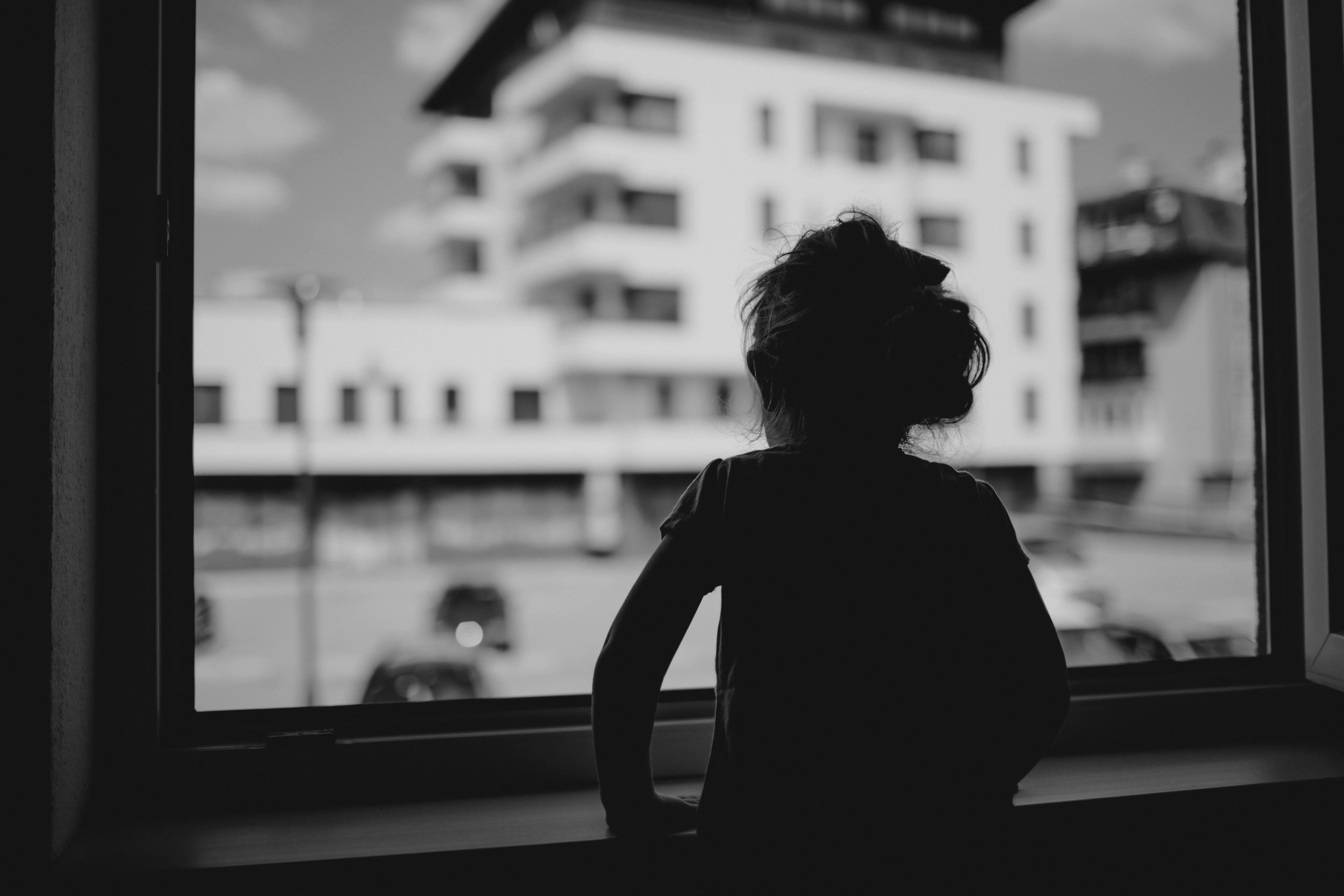 La petite fille de trois ans, Lana, regarde par la fenêtre son jardin d'enfants
