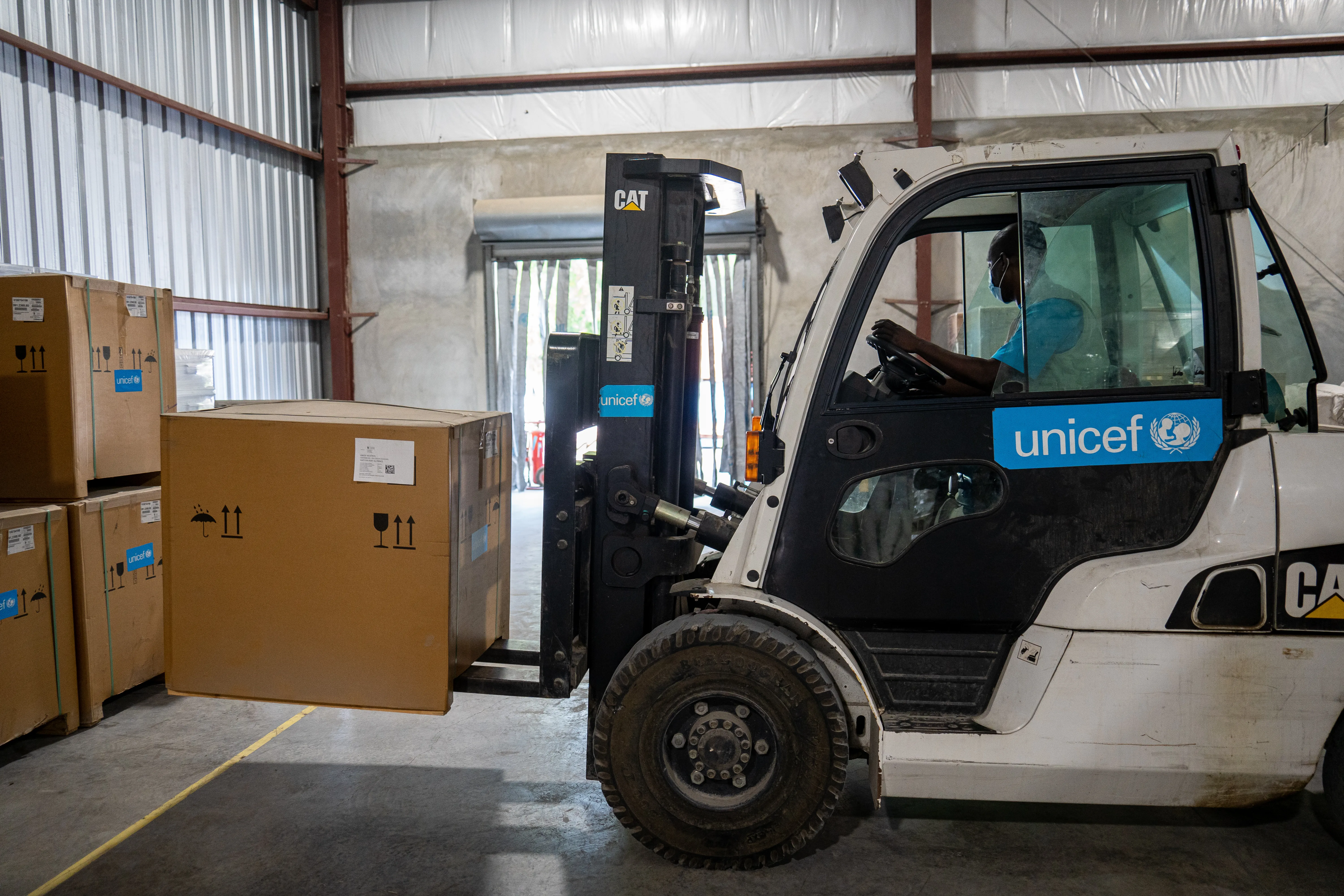 UNICEF Haiti supply officer Jeremie Thomas fork-lifts a solar fridge in the warehouse in Port-au-Prince.