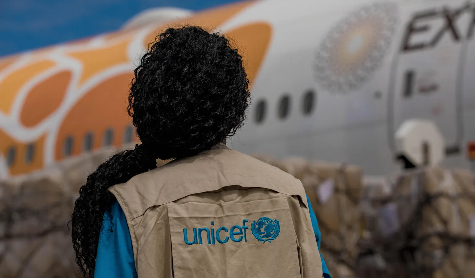 A UNICEF staff member watches as COVID-19 vaccines are unloaded from a plane.