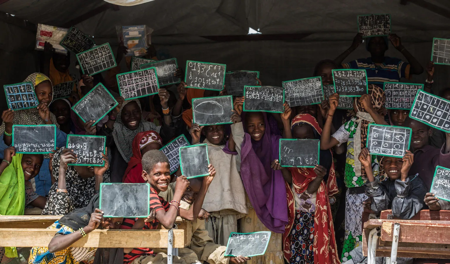 Children show off writing samples on slates.