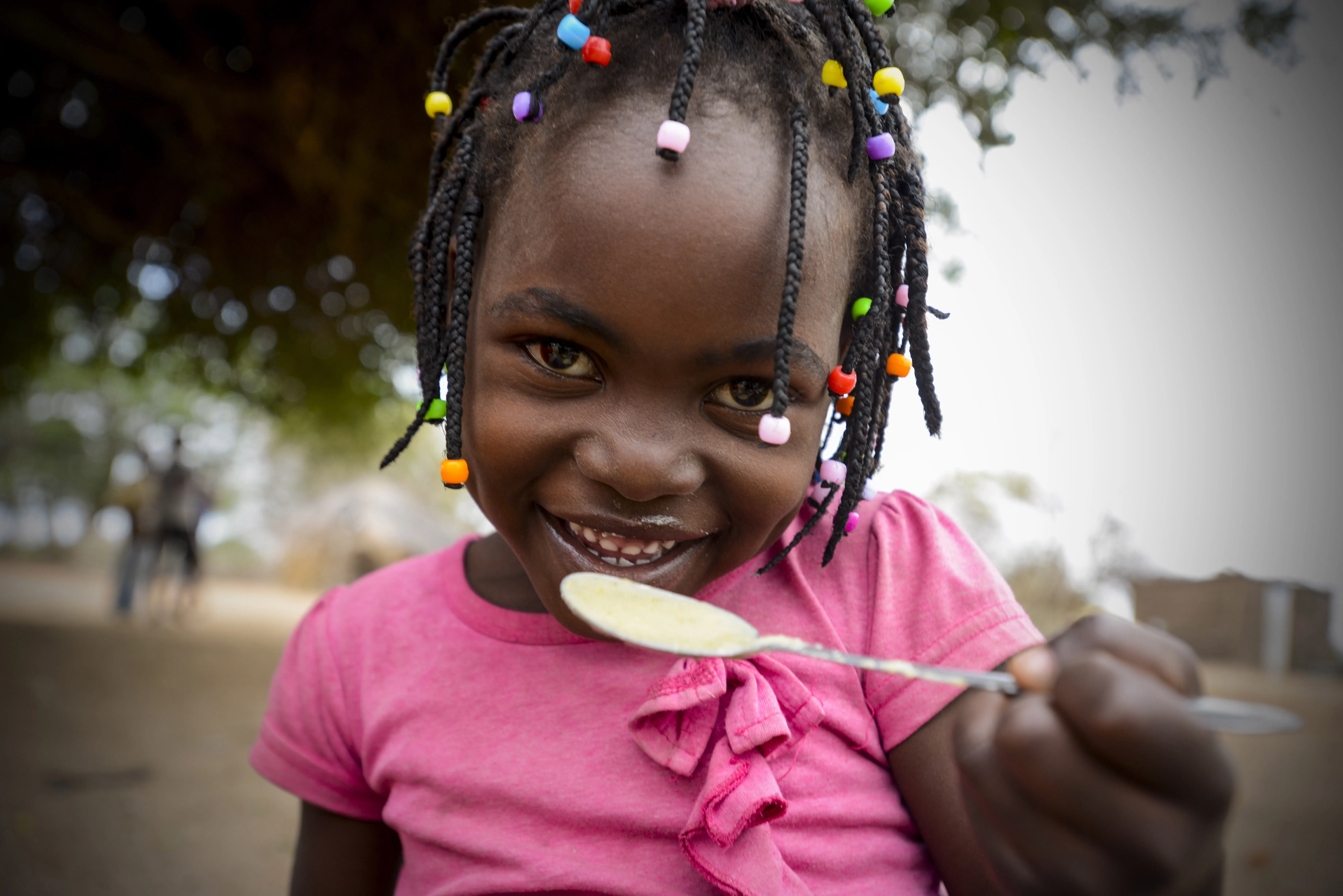 A child smiles as she eats a meal at the school in Mbuene village, Magude district, Maputo Province, Mozambique