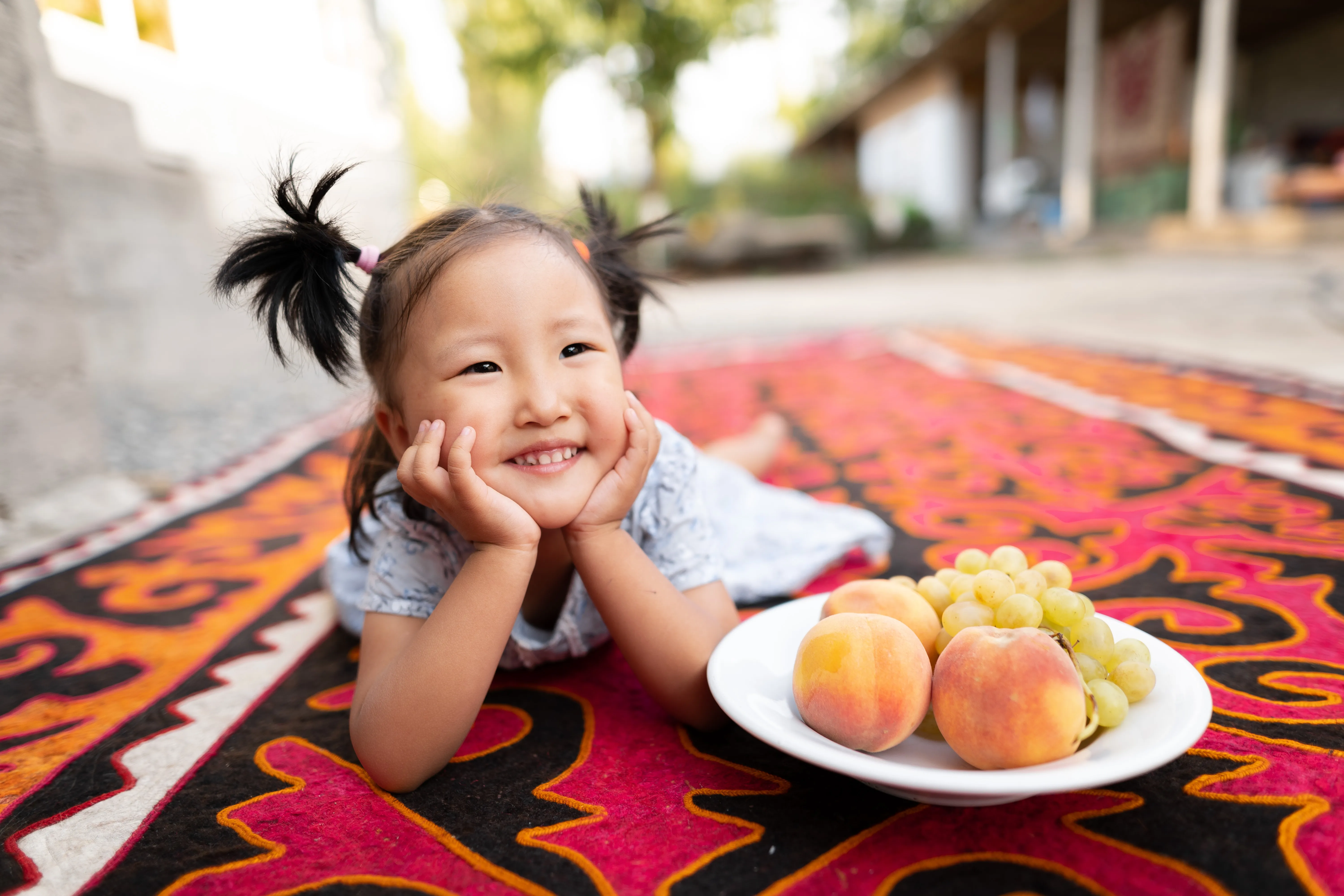 A little girl poses with a bowl of fresh fruits.