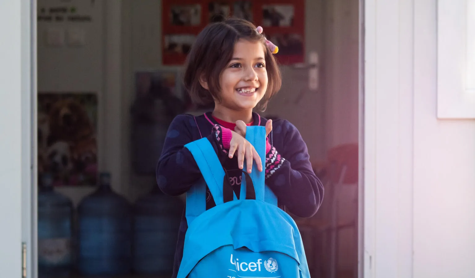 A young girl holds her UNICEF-supplied backpack.