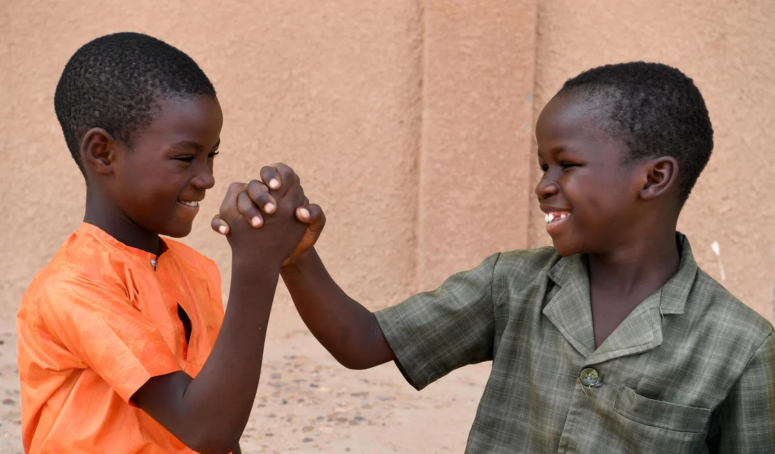 Two boys hold hands outside a school in Niger